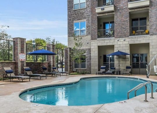 a swimming pool with chairs and umbrellas in front of a building at 17 Broad, Chattanooga, TN 37408