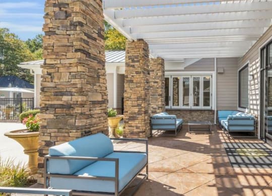 a covered patio with blue chairs and a stone wall at Marina Point, Chattanooga, TN 37415
