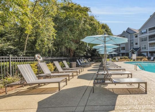 a pool with chairs and umbrellas in front of a building at Marina Point, Chattanooga