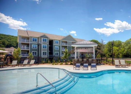 a swimming pool with chairs and a building in the background  at Lullwater at Big Ridge, Hixson, Tennessee