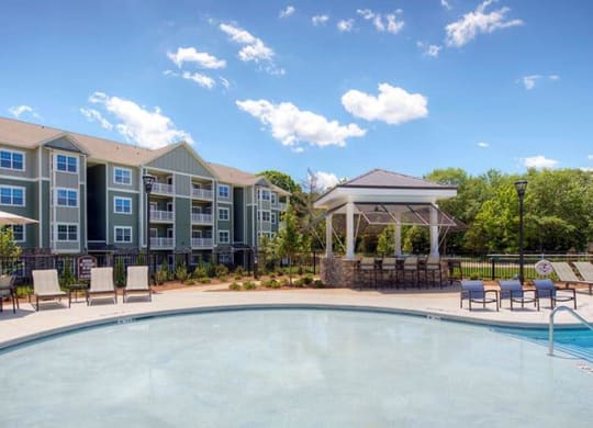 a swimming pool with chairs and umbrellas next to an apartment building  at Lullwater at Big Ridge, Tennessee, 37343