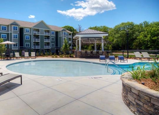 a swimming pool with chairs and a building in the background  at Lullwater at Big Ridge, Hixson, Tennessee