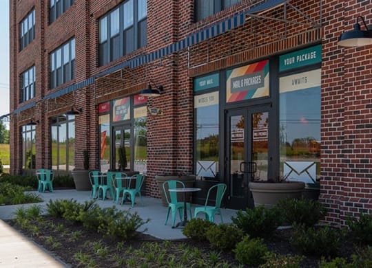 a brick building with green chairs in front of it at Livingston Flats Apartments, Chesterfield, VA