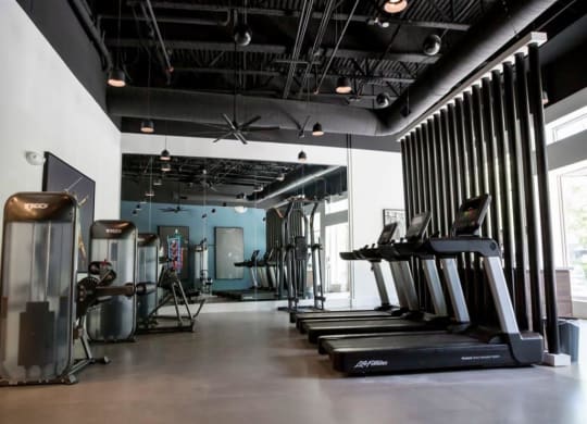 a gym with treadmills and other exercise equipment at Flats at West Broad Village, Glen Allen