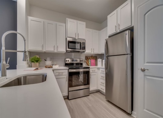 a kitchen with white cabinets and stainless steel appliances at Flats at West Broad Village, Glen Allen, VA