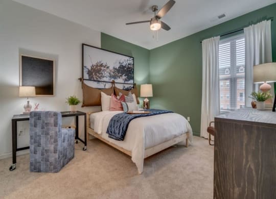 a bedroom with a bed and a chair in front of a window at Flats at West Broad Village, Glen Allen, 23060