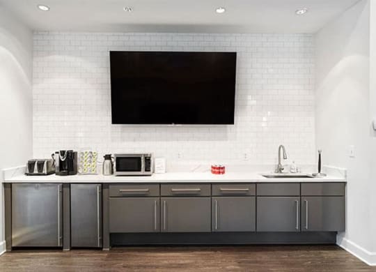 a kitchen with a sink a microwave and a television at Trails at Short Pump Apartments, Richmond, VA