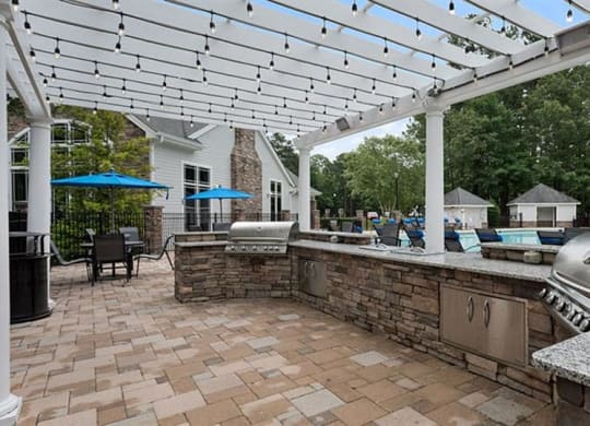 a patio with a grill and a pool in the background at Trails at Short Pump Apartments, Richmond