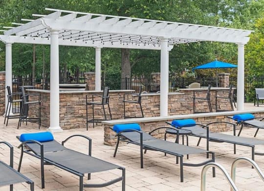 a patio with a bunch of chairs and umbrellas at Trails at Short Pump Apartments, Richmond, Virginia