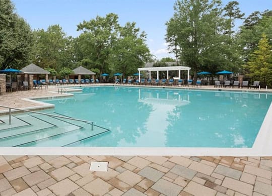 a large swimming pool with umbrellas and chairs around it at Trails at Short Pump Apartments, Virginia,23233