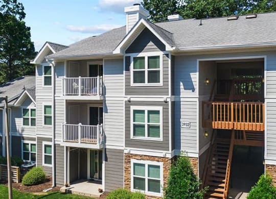 a gray apartment building with green trees in the background at Trails at Short Pump Apartments, Richmond, Virginia