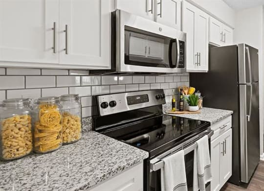 a kitchen with a stove top oven next to a refrigerator at Trails at Short Pump Apartments, Virginia,23233