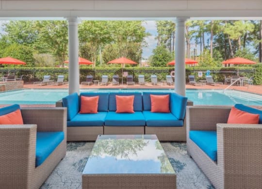 a poolside lounge area with blue couches and orange pillows at Sterling Manor, Williamsburg, VA