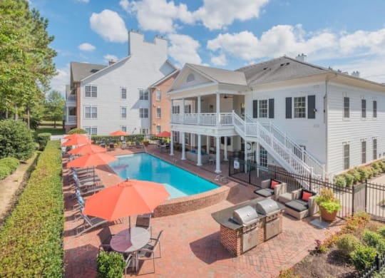 a swimming pool with umbrellas and chairs in front of a house at Sterling Manor, Virginia