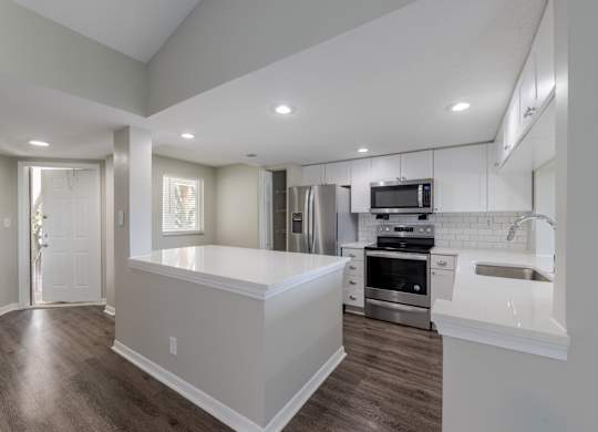 A modern kitchen with stainless steel appliances and a breakfast bar.