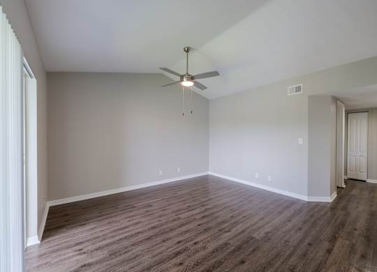 A room with a ceiling fan and wooden flooring.