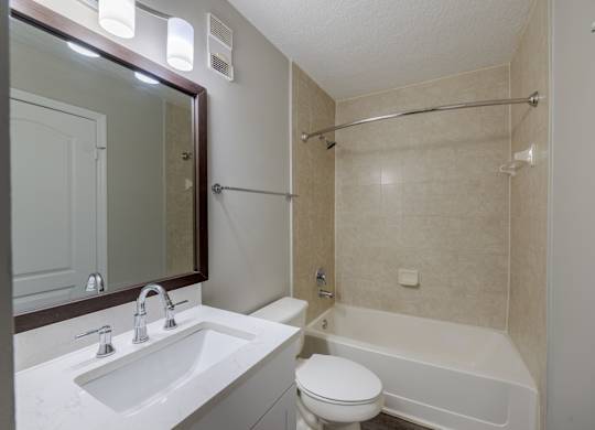 A white toilet sits next to a white sink in a bathroom.