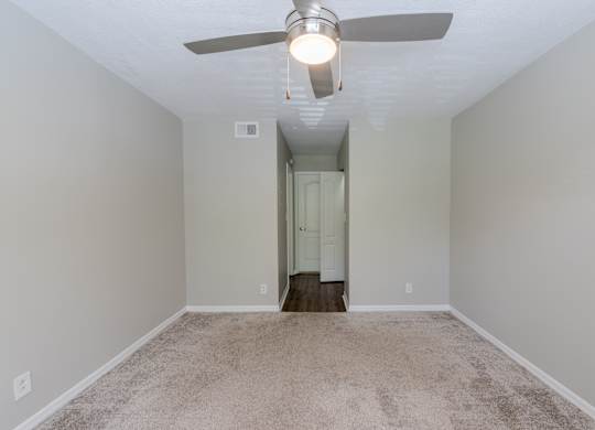 A room with a ceiling fan and carpeted floor.