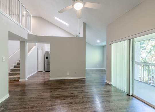 A spacious living room with a staircase and sliding glass doors.