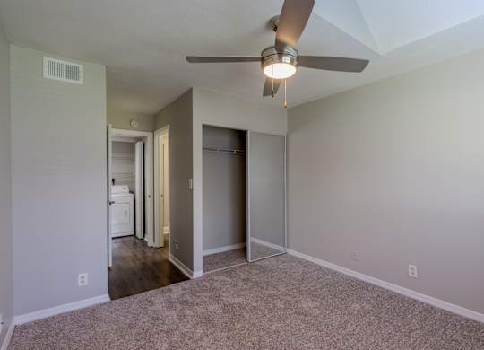 A room with a ceiling fan and carpeted floor.