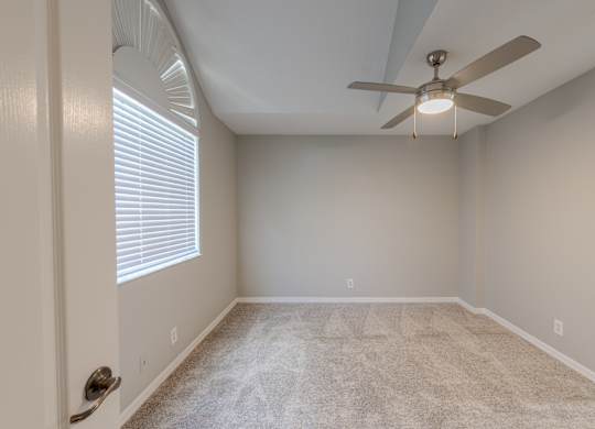 A room with a ceiling fan and carpeted floor.