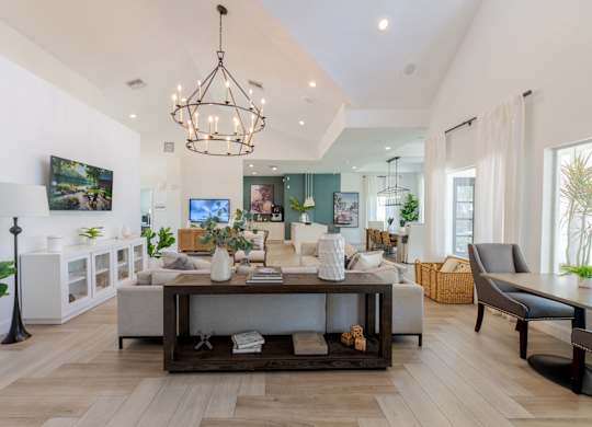 A modern living room with a white sofa set and a chandelier.