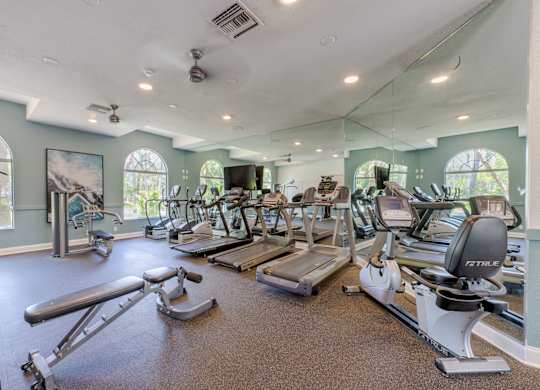 A gym with a variety of equipment including treadmills, weights, and exercise machines.