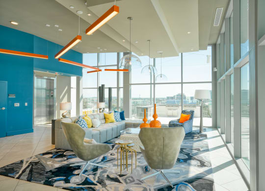 a living room with blue and yellow furniture and large windows at Vista Brooklynn Apartments, Florida
