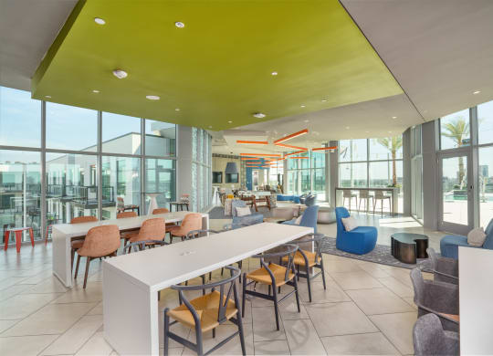 a lounge area with tables and chairs and large windows at Vista Brooklynn Apartments, Jacksonville, FL, 32202
