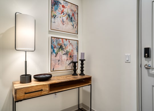 a console table with a lamp and paintings on the wall at Vista Brooklynn Apartments, Jacksonville, 32202