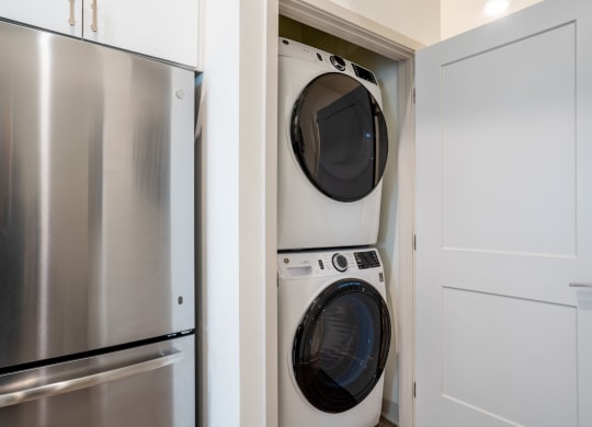 a small laundry room with a washer and dryer and a stainless steel refrigerator at Vista Brooklynn Apartments, Jacksonville
