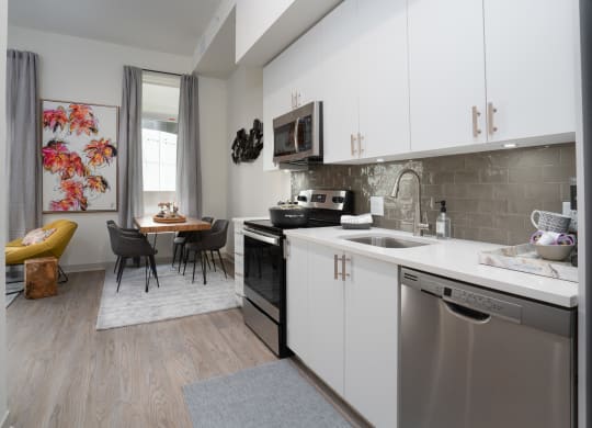a kitchen with white cabinets and stainless steel appliances and a dining room with a table at Vista Brooklynn Apartments, Jacksonville, FL, 32202