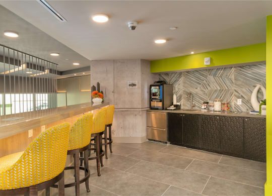 a long bar with yellow chairs and a counter in a lobby at Vista Brooklynn Apartments, Jacksonville, 32202