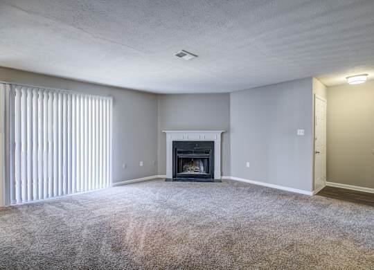 A living room with a fireplace and carpeted floor.