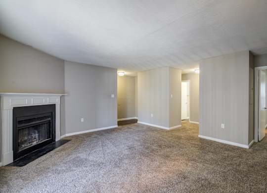 A spacious living room with a fireplace and carpeted floor.