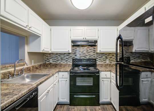 A kitchen with black appliances and white cabinets.