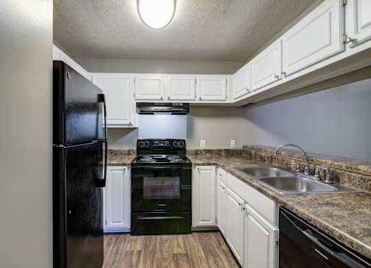 A kitchen with a black refrigerator, stove, and oven.