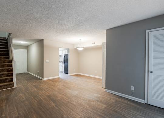 A room with wooden floors and a staircase leading to another room.