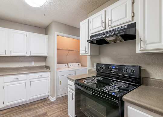 A kitchen with white cabinets and a black stove top oven.