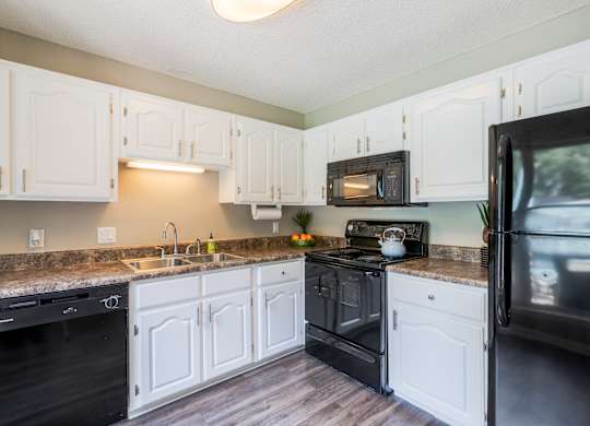 A kitchen with white cabinets and black appliances.