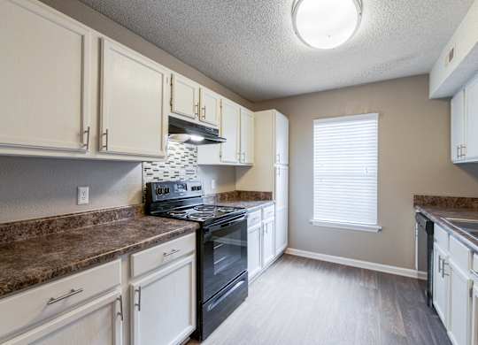 A kitchen with a black oven and brown countertops.