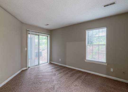 A room with a carpeted floor and a window with blinds.