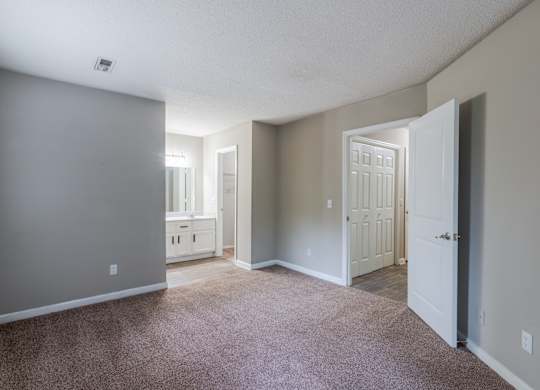 A room with a carpeted floor and a doorway leading to another room.