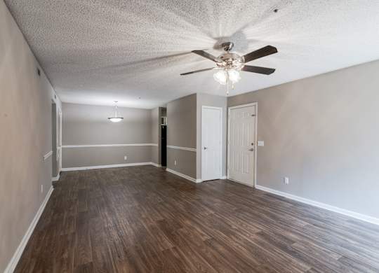 A room with a ceiling fan and wooden flooring.