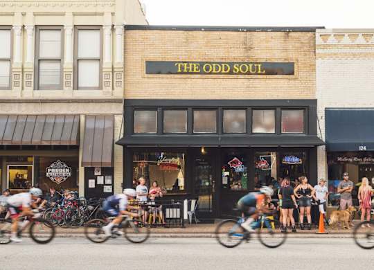 A group of people riding bikes in front of a store called The Odd Soul.