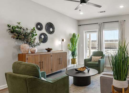 A living room with a green chair, a brown sofa, and a ceiling fan.