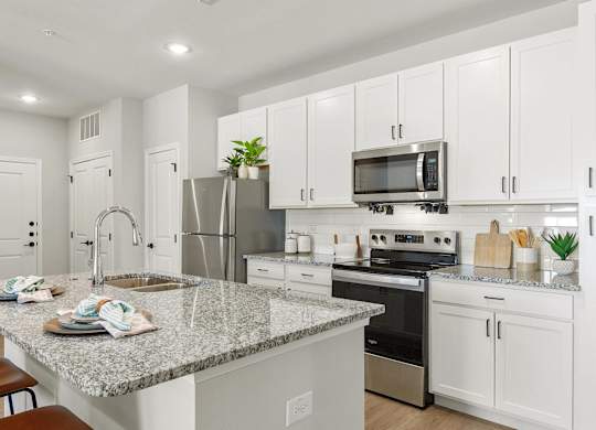 A modern kitchen with white cabinets and a granite countertop.