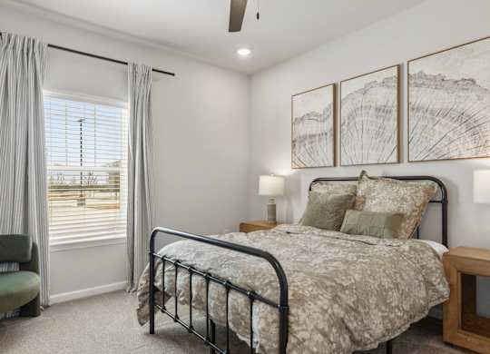 A bedroom with a bed, chair, and a window with curtains.
