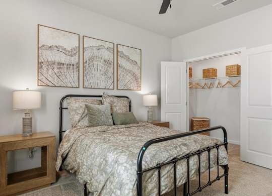 A bedroom with a bed, nightstand, and a wall art of a landscape.