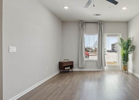 A room with a ceiling fan and a window with curtains.